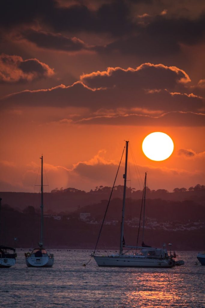Sunset view of sailboats in Brixham harbor, creating a serene maritime scene.